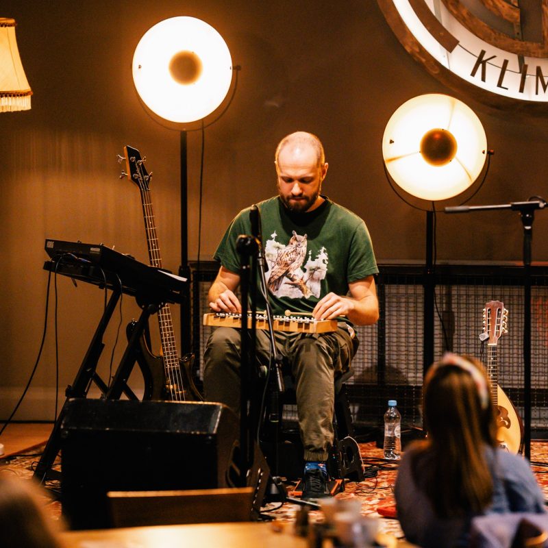 muzyk grający na dzwonkach chromatycznych na scenie, dookoła inne instrumenty