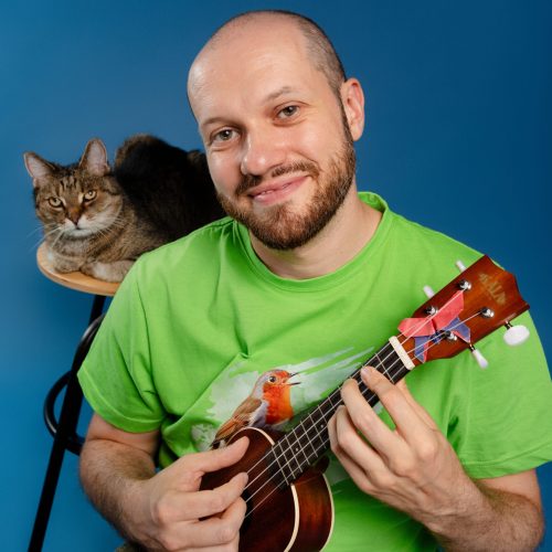 muzyk grający na mandolinie z kotem na krześle